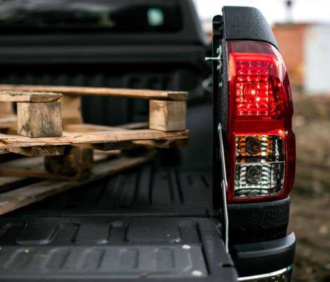 Back of a pick-up truck. Wooden beams sitting in the back of the truck.